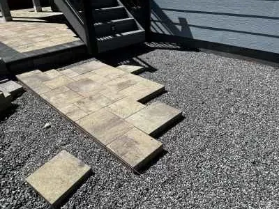 Placing pavers by hand along string lines on a prepared base