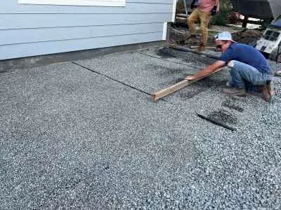 Screeding a compacted angular-gravel paver base with string lines