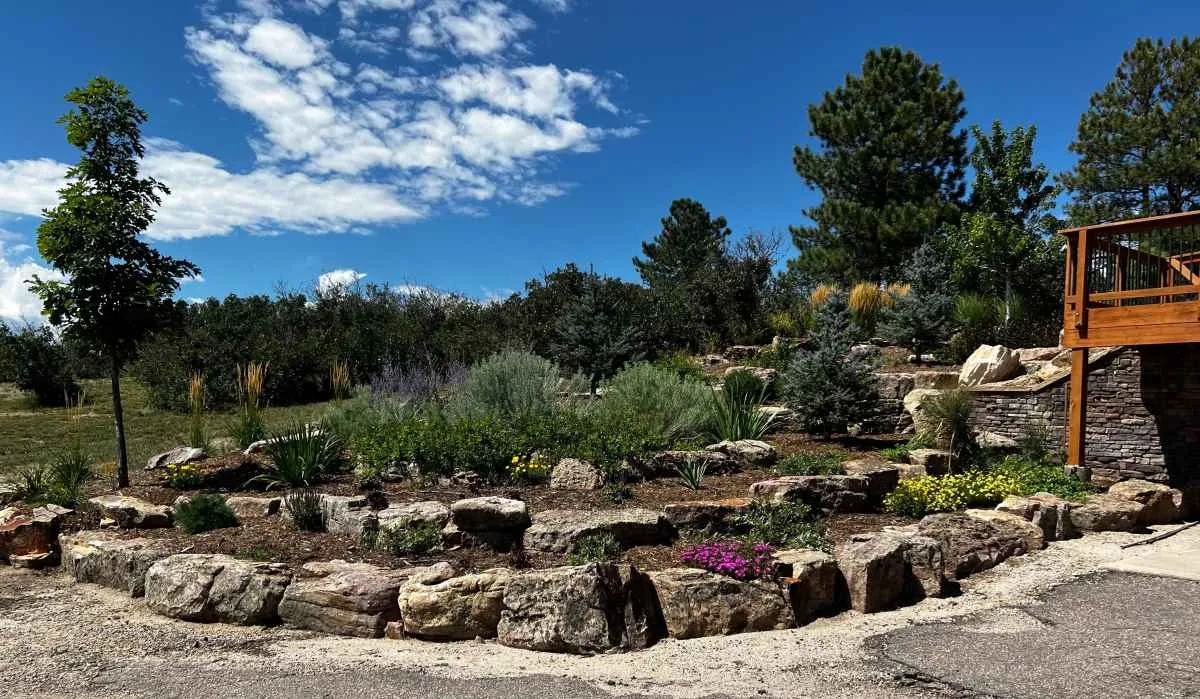 Large natural boulders terracing a planted slope beside a deck