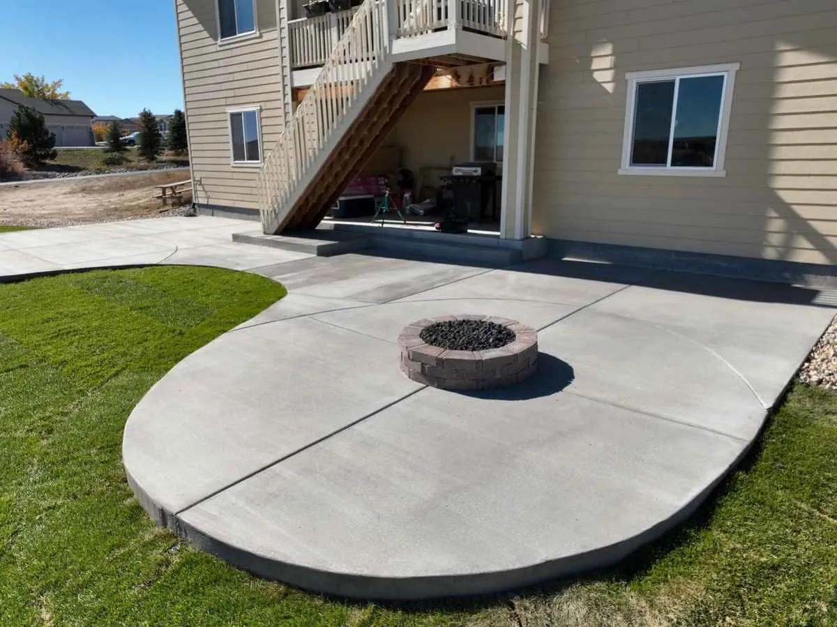 Round built-in masonry fire pit centered on a curved broom-finish concrete patio