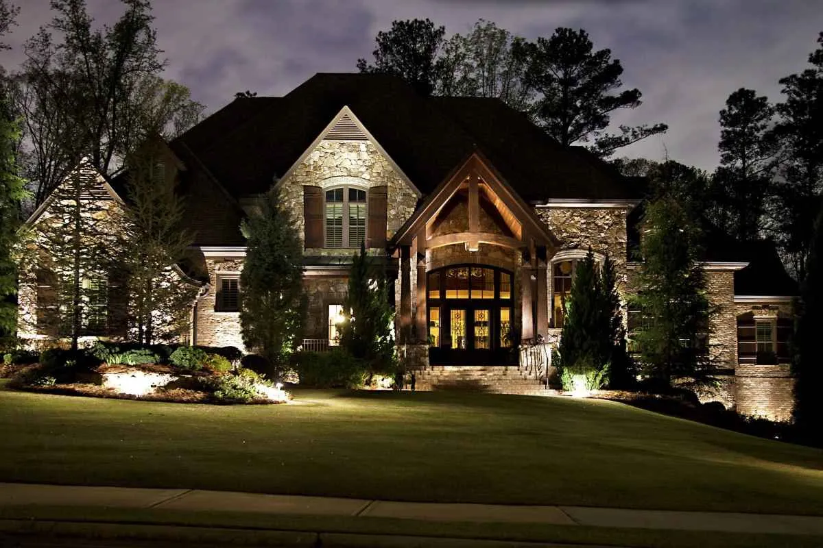 Stone entry and front landscape illuminated from multiple directions at night