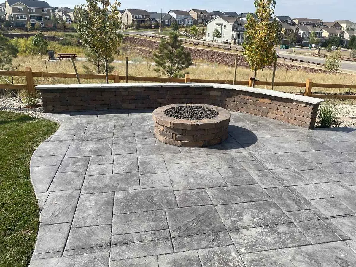 Round built-in masonry fire pit on a paver patio inside a curved block seating wall
