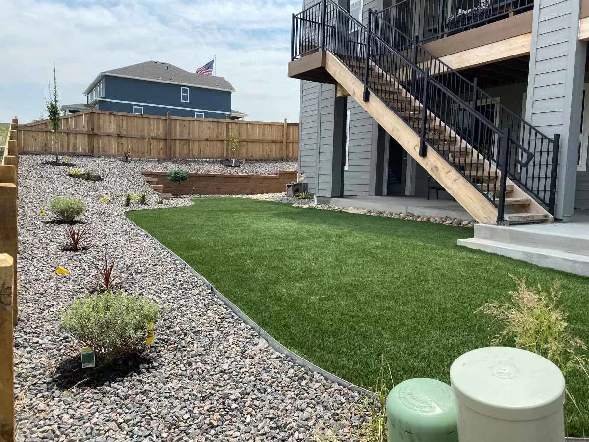 The same sloped backyard after turf, rock, and retaining-wall installation