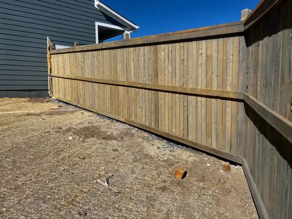Back of a wood privacy fence with rails and posts following a residential grade change