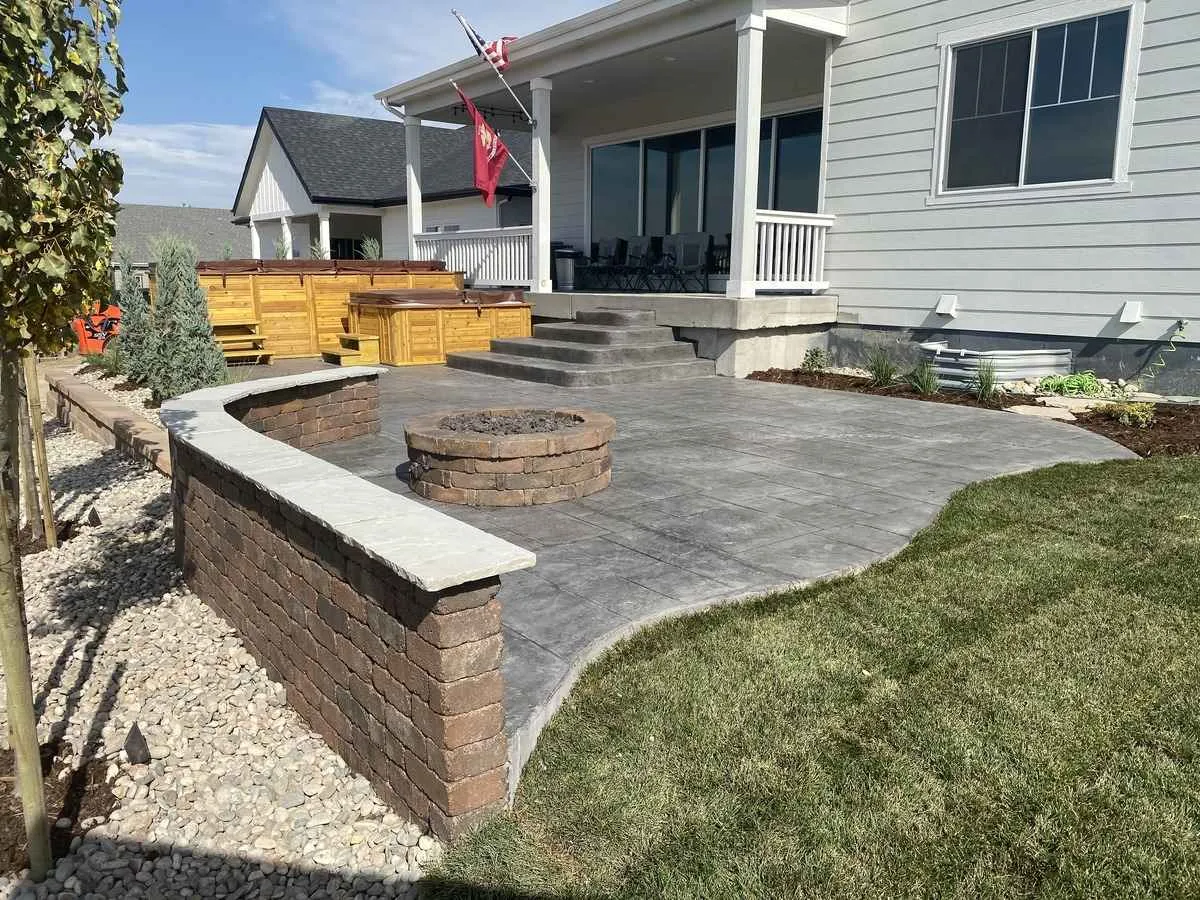 Completed landscape with stamped concrete patio, fire pit, seating wall, and planting