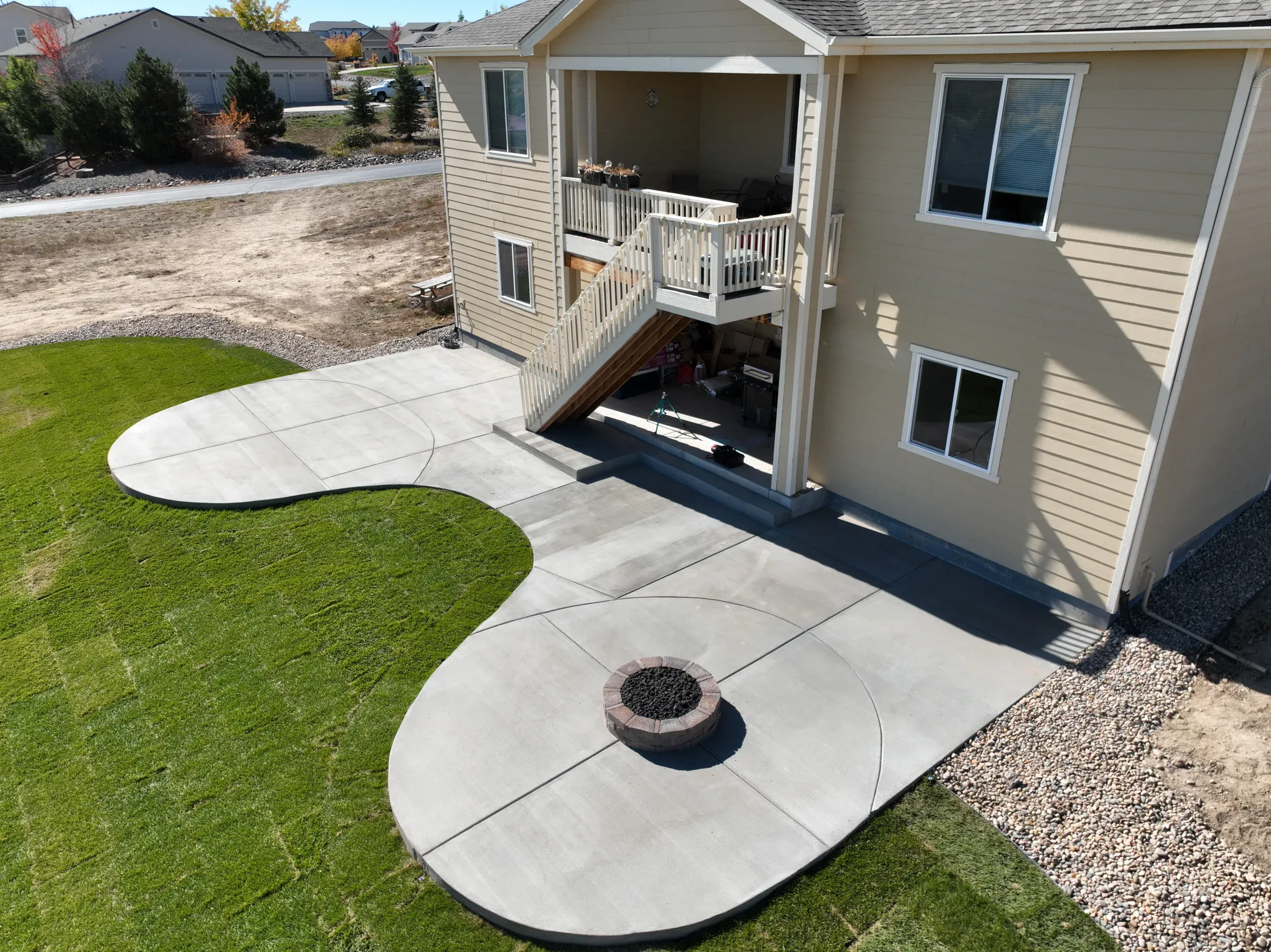Aerial view of a curved concrete patio with a fire pit and new sod lawn in Elizabeth