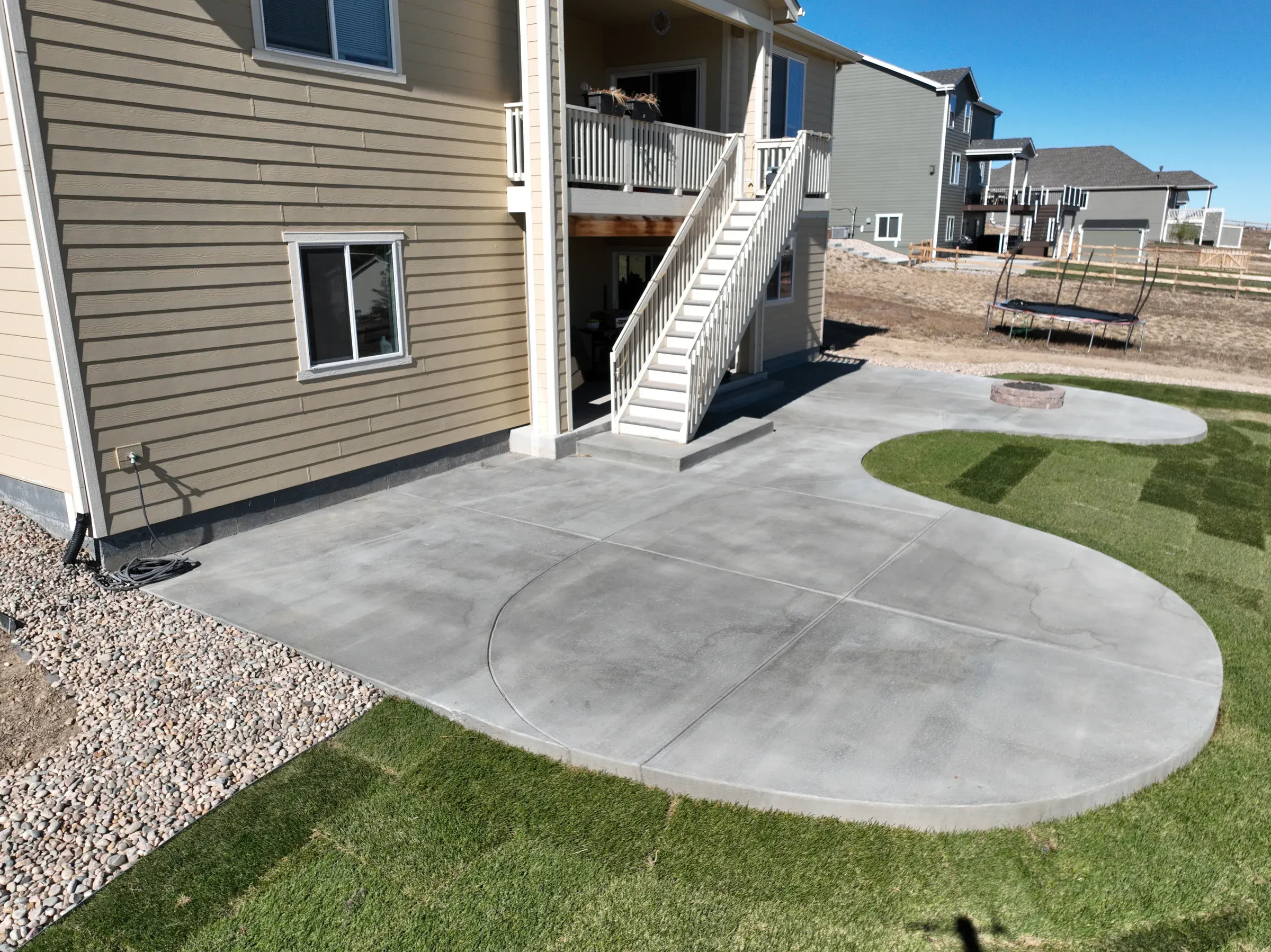 Curved concrete patio with a fire pit bordered by new sod in Elizabeth