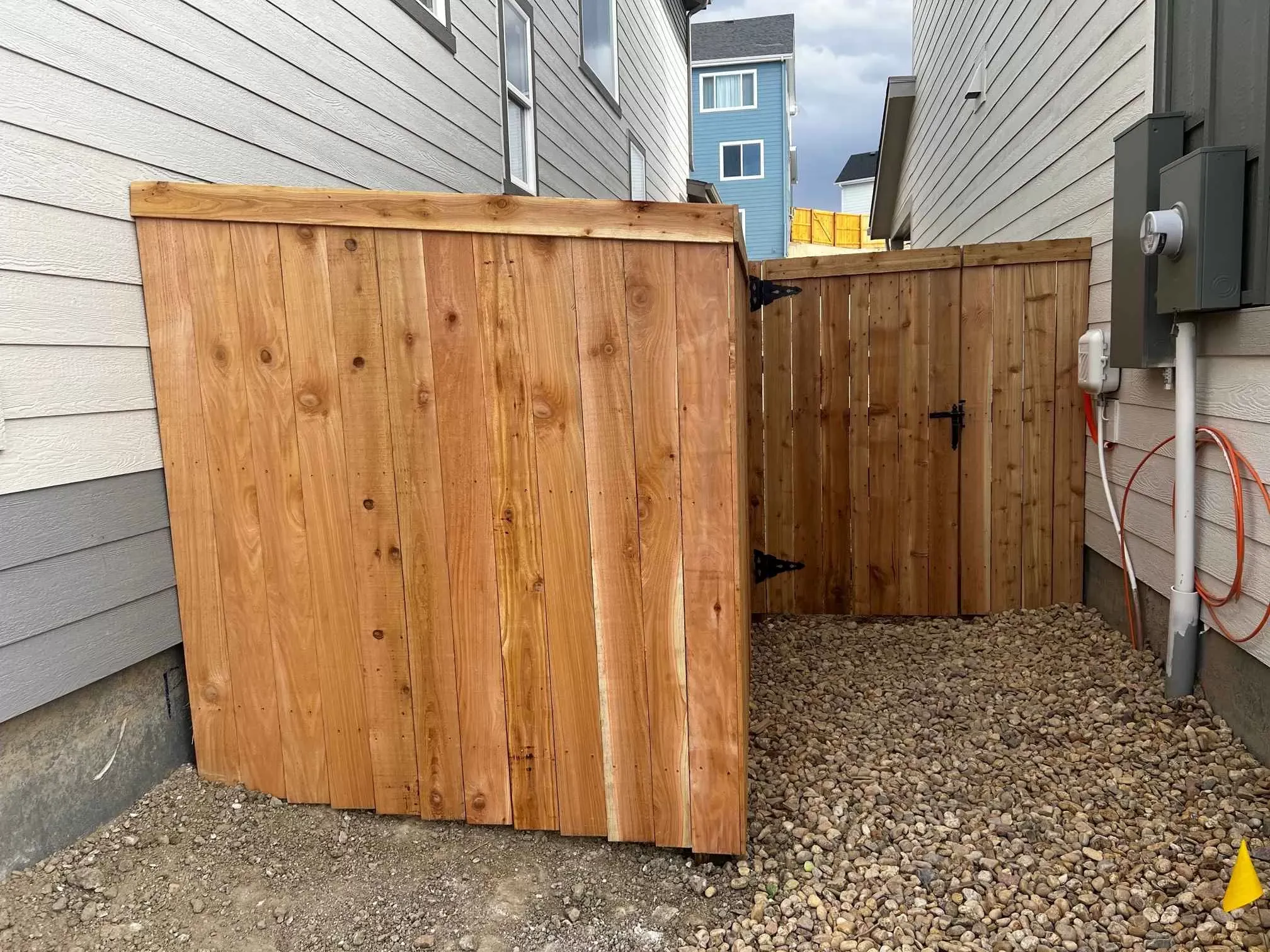 Cedar privacy fence panels with a hinged wood gate installed between two homes