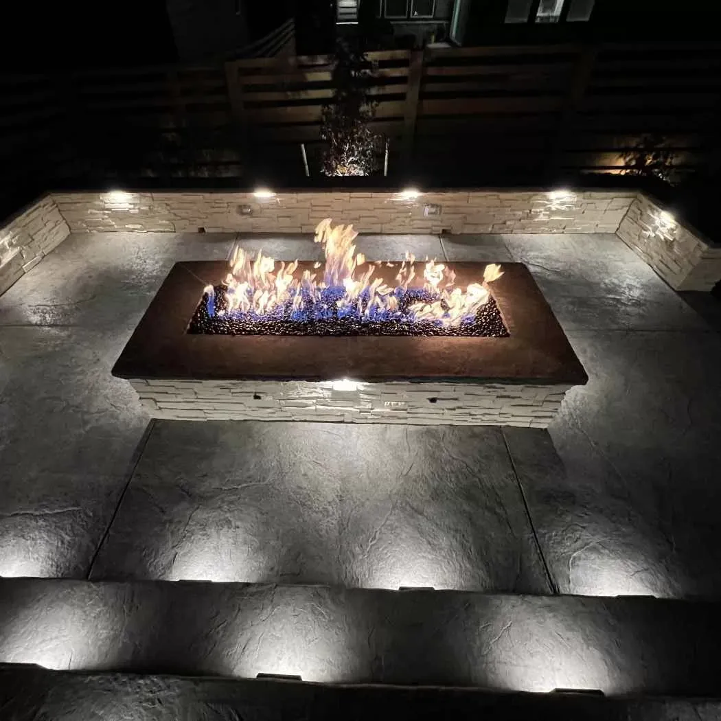 Fire pit surrounded by seat wall and landscape lighting
