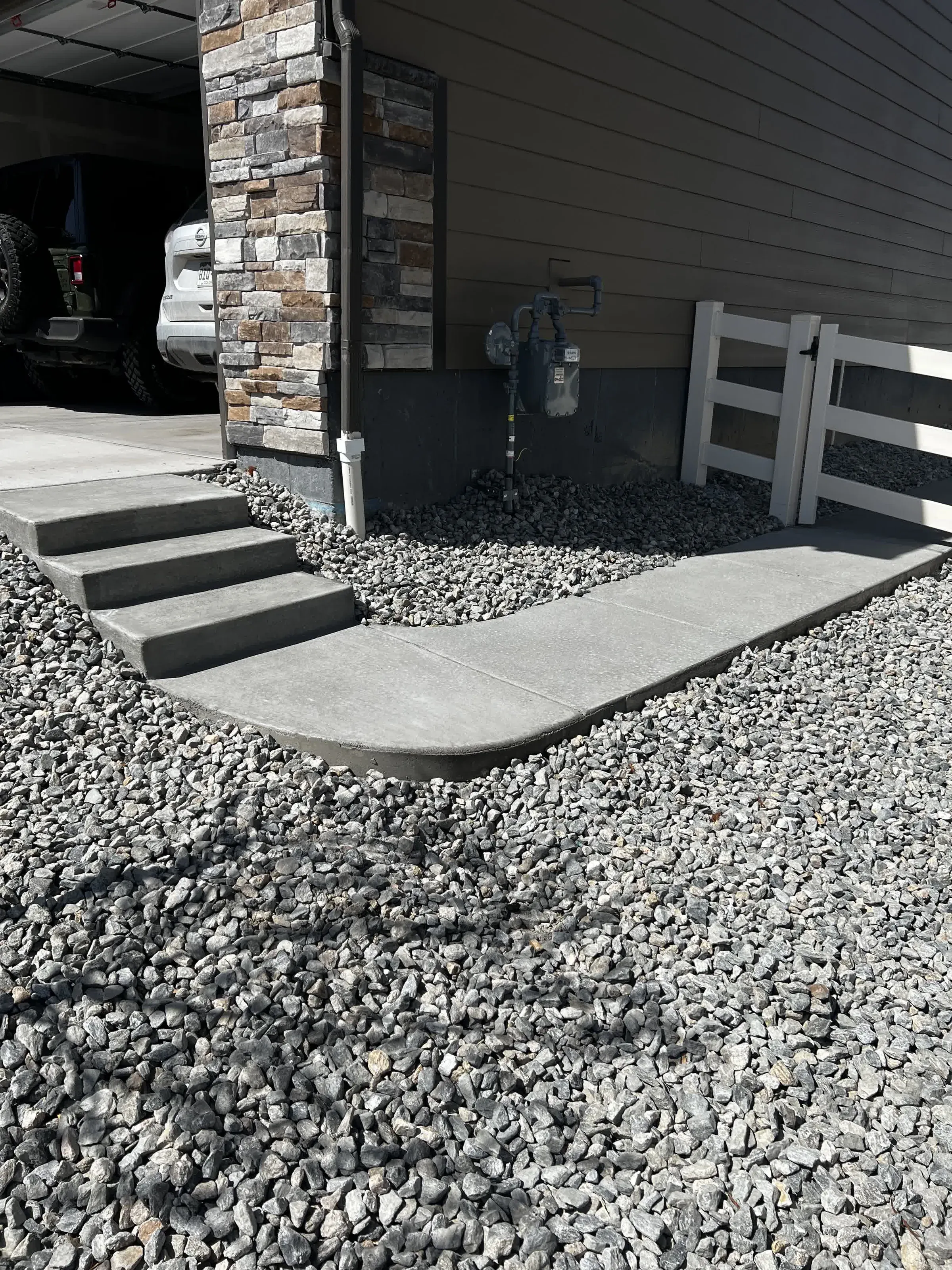 Concrete walkway and steps with gray rock landscaping beside a home entrance in Castle Rock