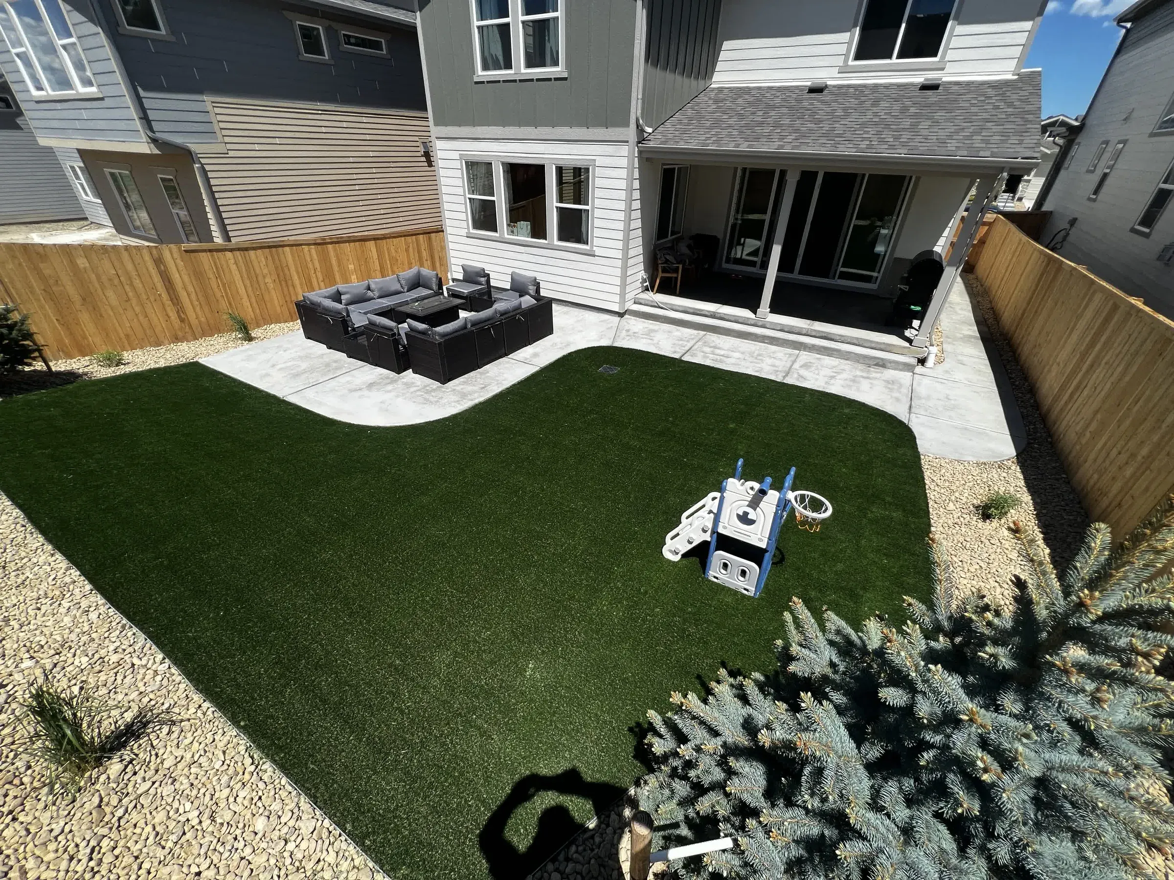 Backyard artificial turf lawn with a concrete patio and outdoor sectional seating in Parker