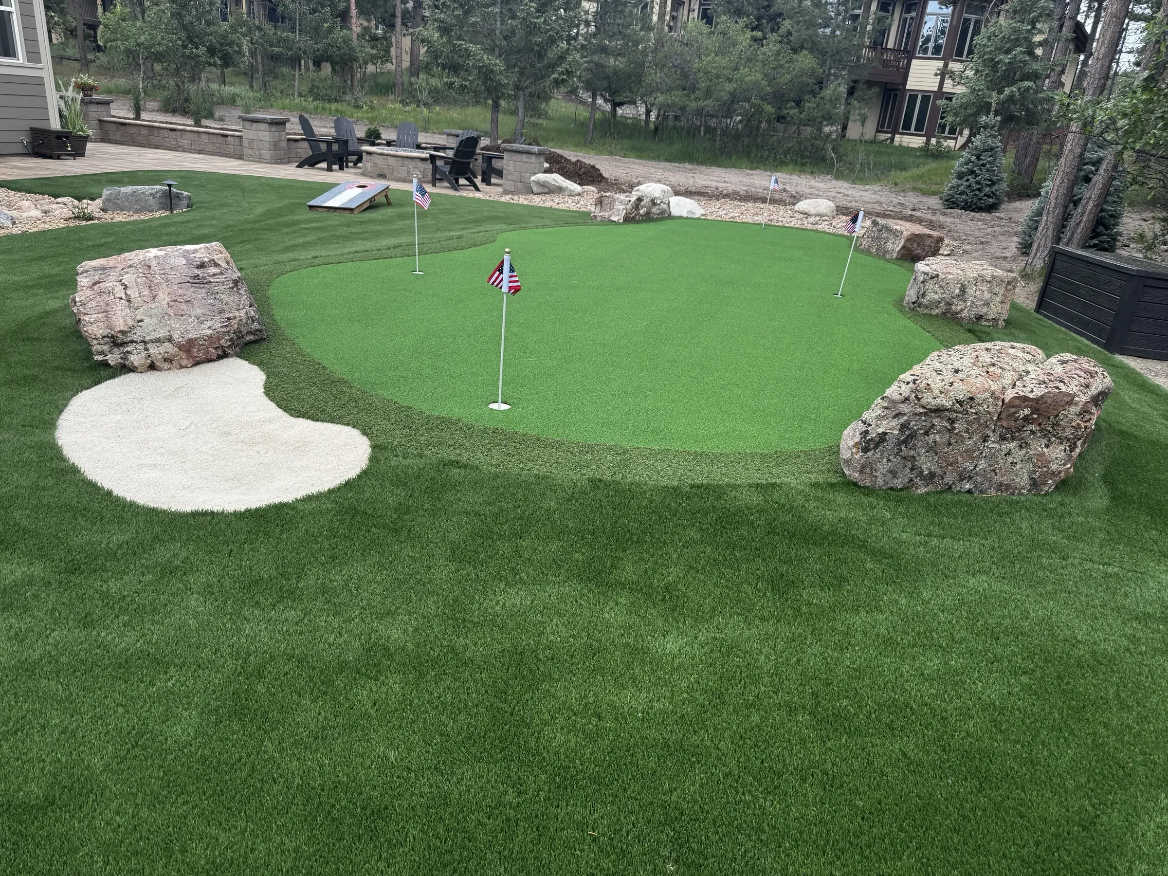 Artificial turf putting green with a synthetic sand bunker and boulder edging in Larkspur