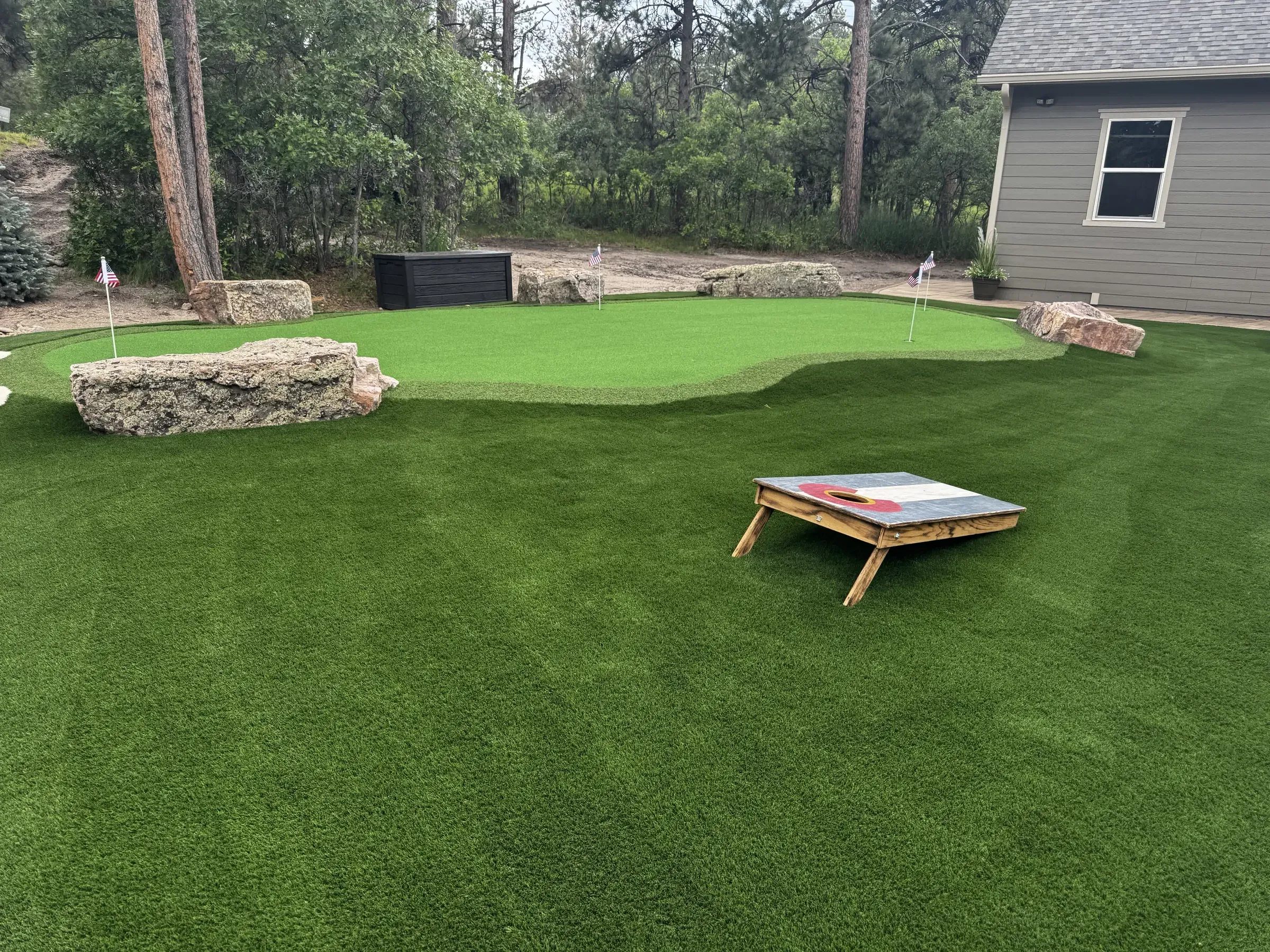 Wide view of an artificial turf backyard with boulder landscaping in Larkspur