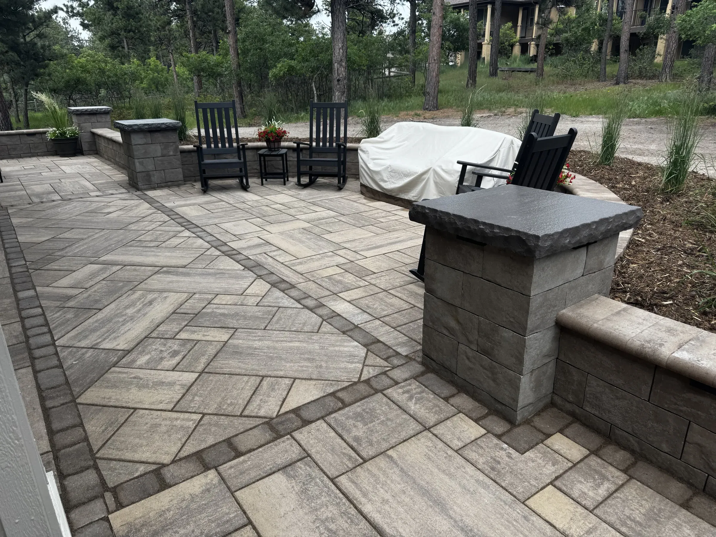 Paver patio seating area with a herringbone pattern and stone pillars in Larkspur
