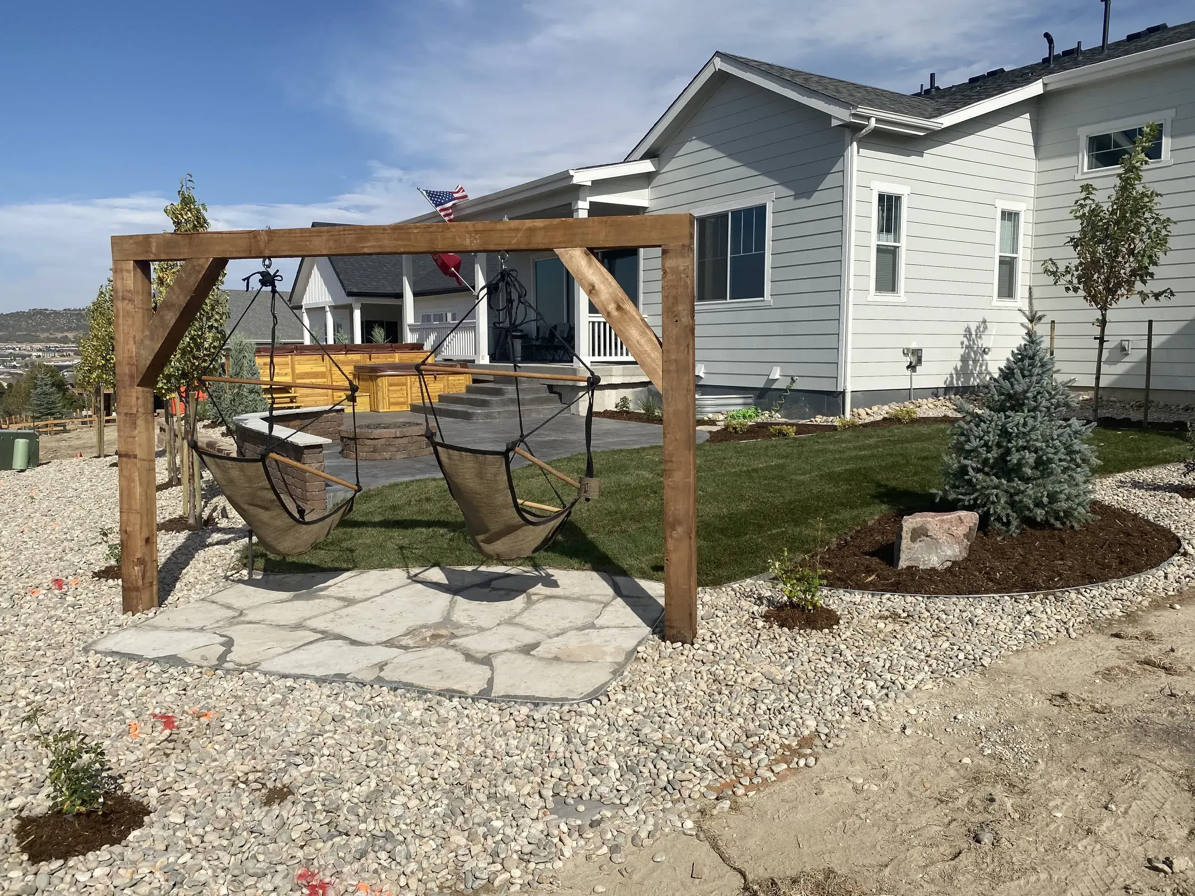Completed backyard renovation in Castle Rock with a flagstone patio, hanging chair swing, and stonework planting beds