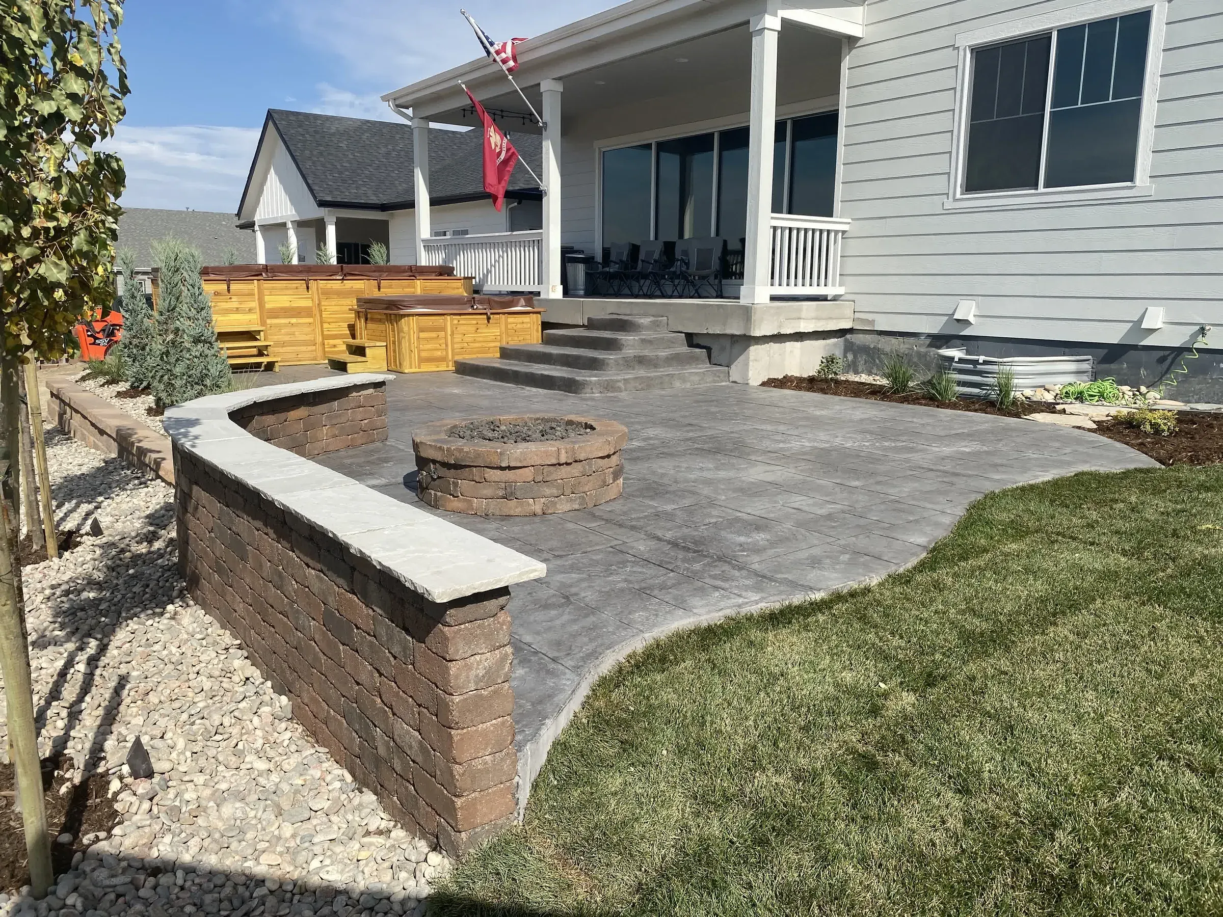 Stamped concrete patio with a curved paver seat wall and fire pit in Castle Rock