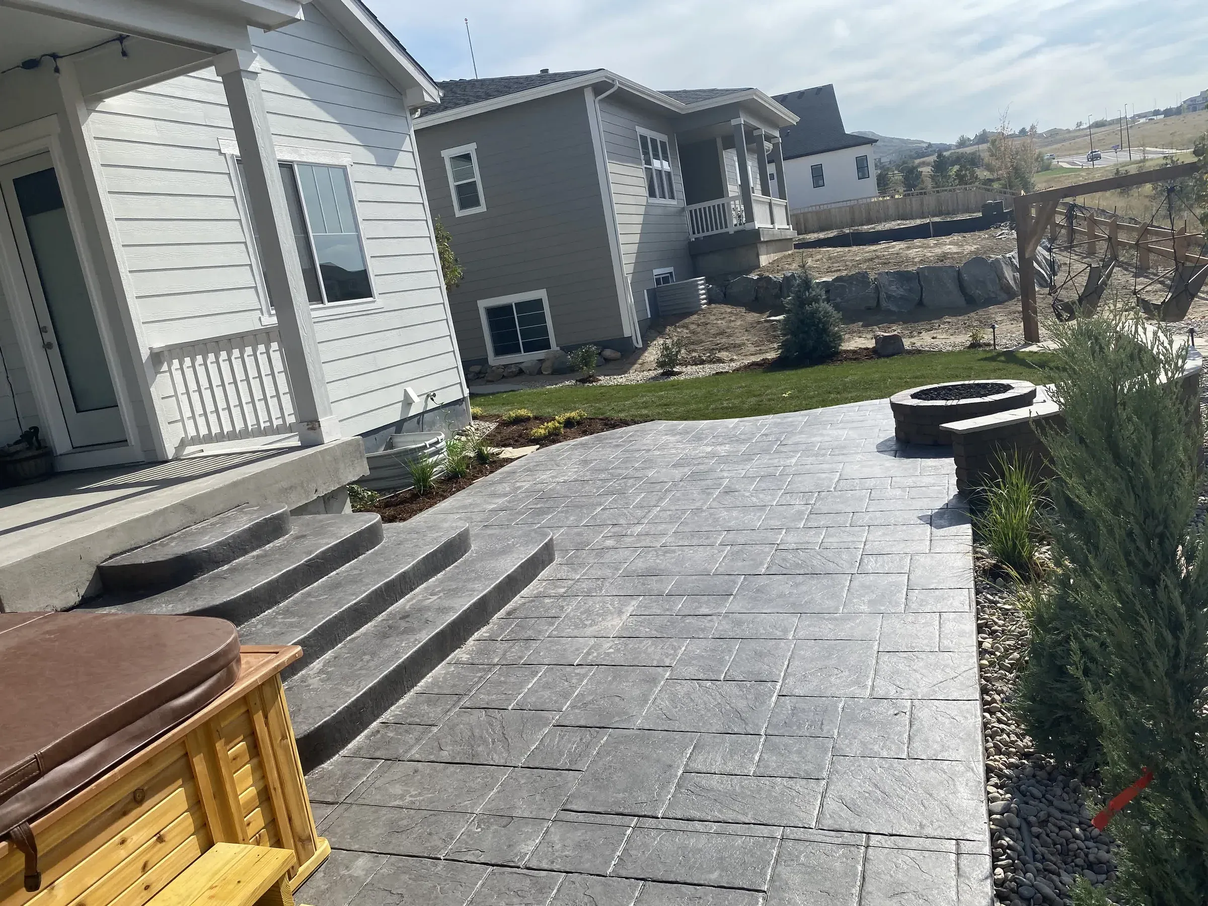 Stamped concrete patio steps leading to a fire pit and boulder retaining wall in Castle Rock