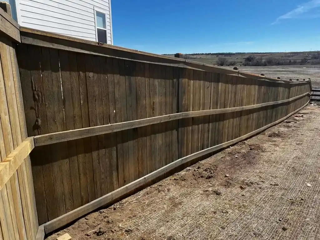 Tall wood privacy fence following a long exposed residential boundary and grade change