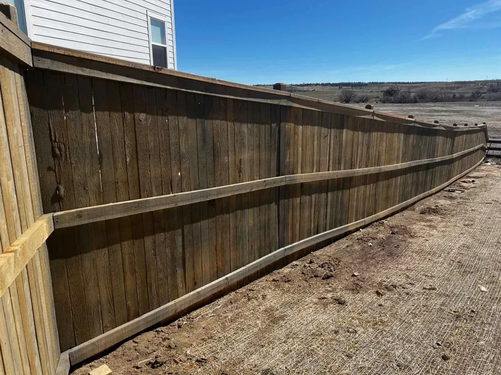 Tall wood privacy fence following a long exposed residential boundary and a change in grade