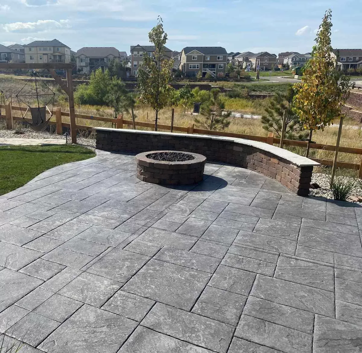 Stamped concrete patio with a curved seating wall and planting beds