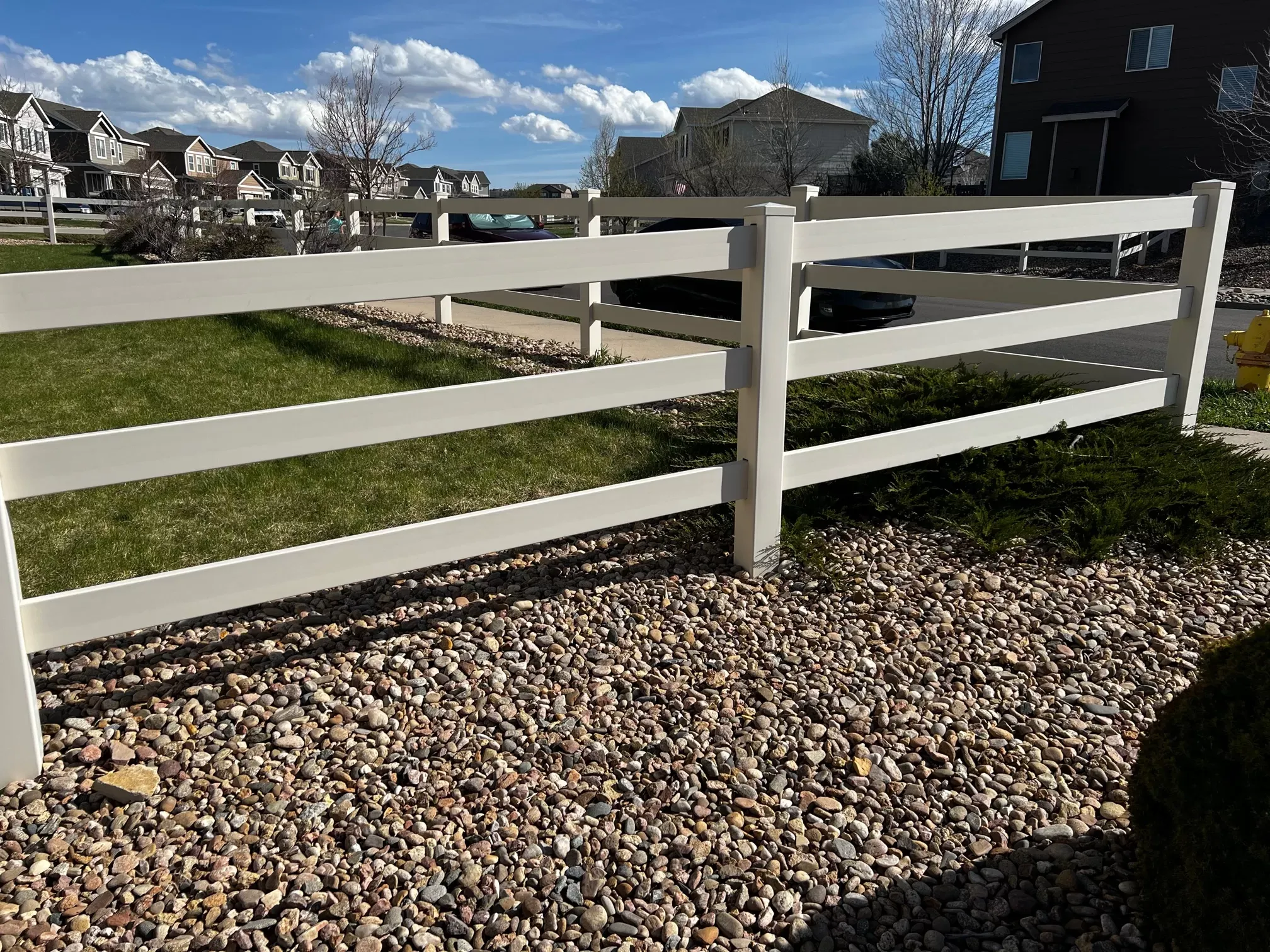 White vinyl three-rail fence along a residential property line